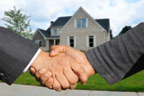 Buyer and seller shaking hands in front of a house