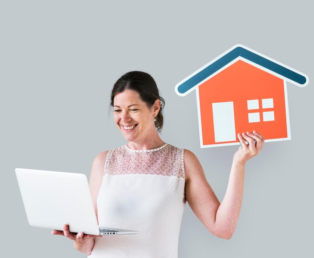 A woman holding a computer and a cardboard house