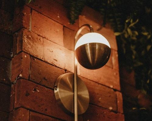 Lampe ronde allumée fixée à un mur de brique