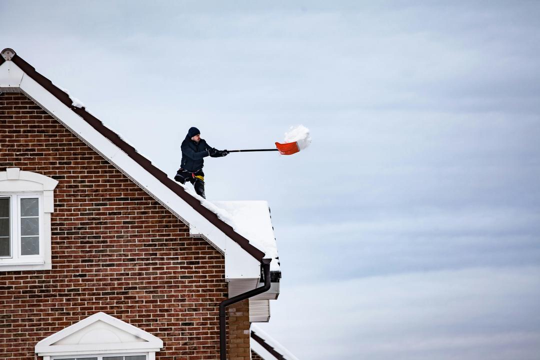 Un homme déneige une toiture