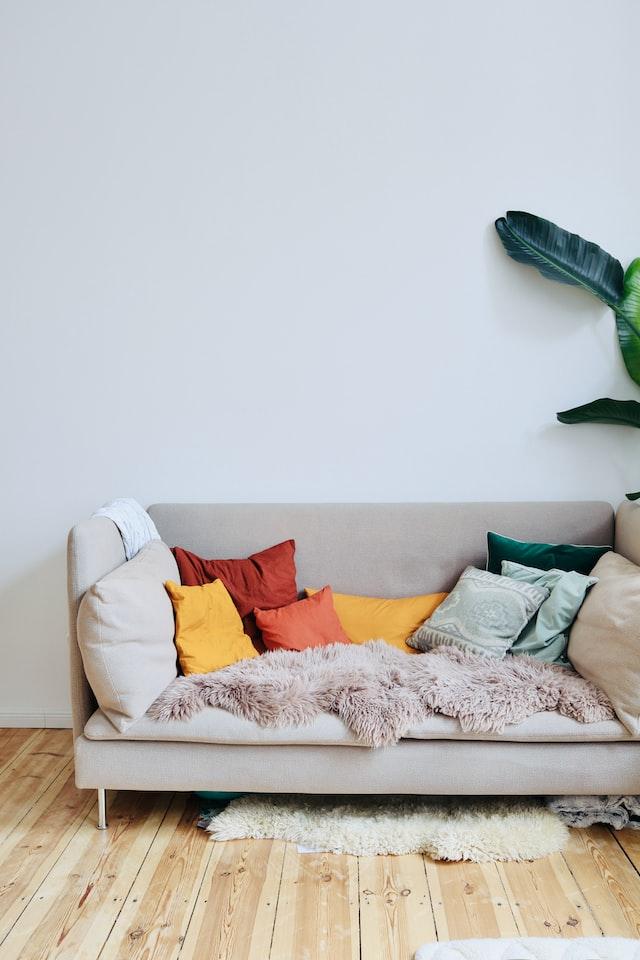 Coussins colorés sur un sofa beige devant un mur pâle
