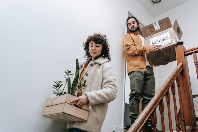 Couple déménageant des boites dans un escalier