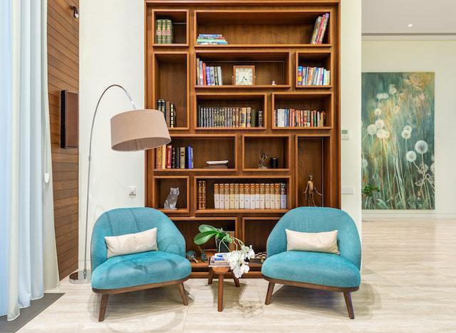 Coin lecture avec deux fauteuils bleus et une grande bibliothèque