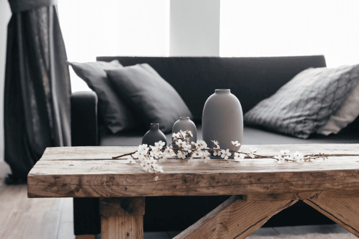 Table basse en bois massif sur laquelle est posée des vases et des fleurs devant un sofa