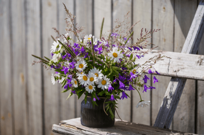 Bouquet de fleurs blanche et mauve dans un vase déposé sur un support en bois usé