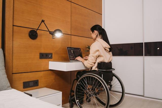 Femme en chaise roulante travaillant à domicile sur un ordinateur portable