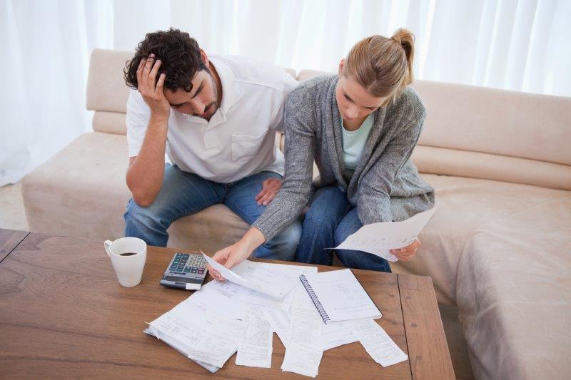 Couplle d'emprunteurs décourageé devant les factures de frais pour l'achat d'une maison
