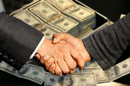 Lenders shaking hand in front of a suitcase full of money