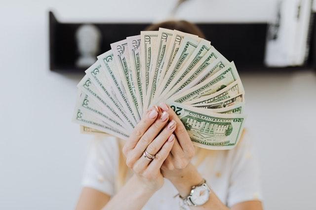 Femme tenant plusieurs billets d'argent en évantail entre ses main