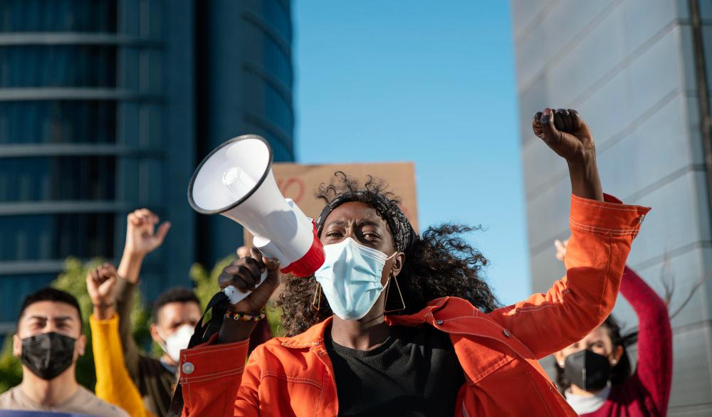 Femme noire tenant un mégaphone pendant une manifestation sur le droit au logement