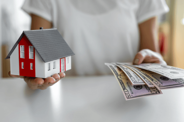 Femme tenant dans ses mains une maison et de l'argent