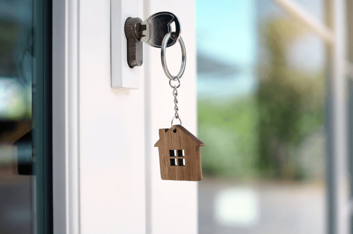 Clé dans une porte avec un porte-clé en forme de maison