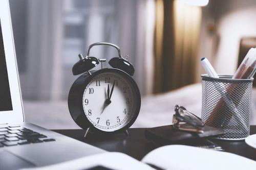 Clock and computer on a desk