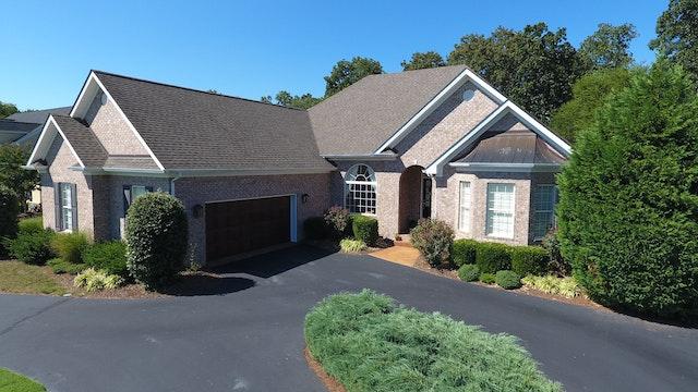 Grande maison avec une entrée pavée en asphalte