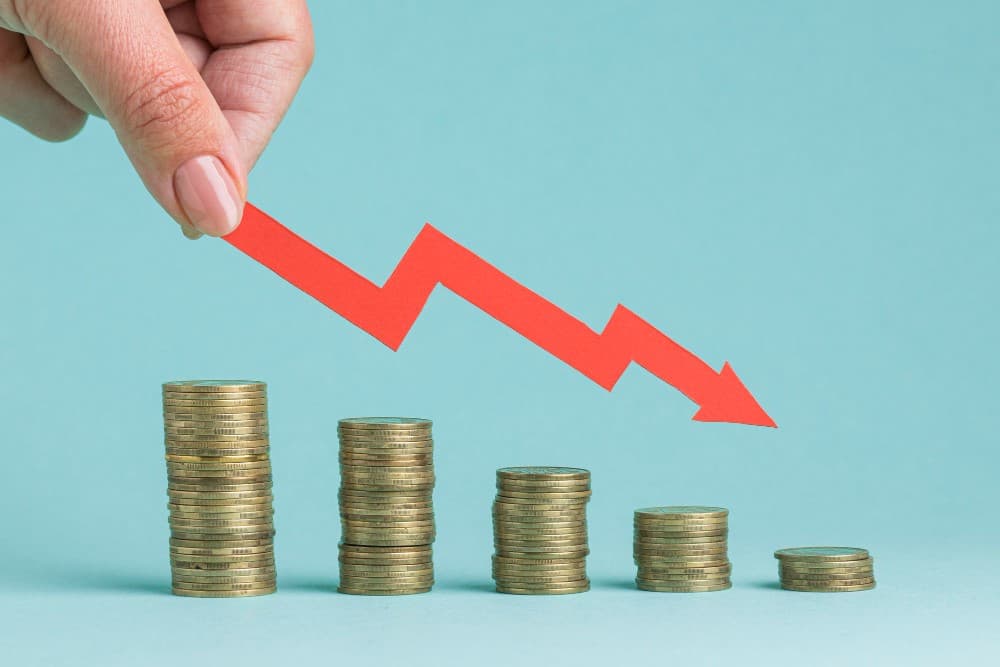 Baisse des taux d’intérêts représentée par des piles d’argent et une flèche vers le bas