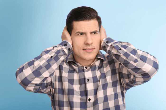 Homme qui se couvre les oreilles en raison d'un bruit trop fort