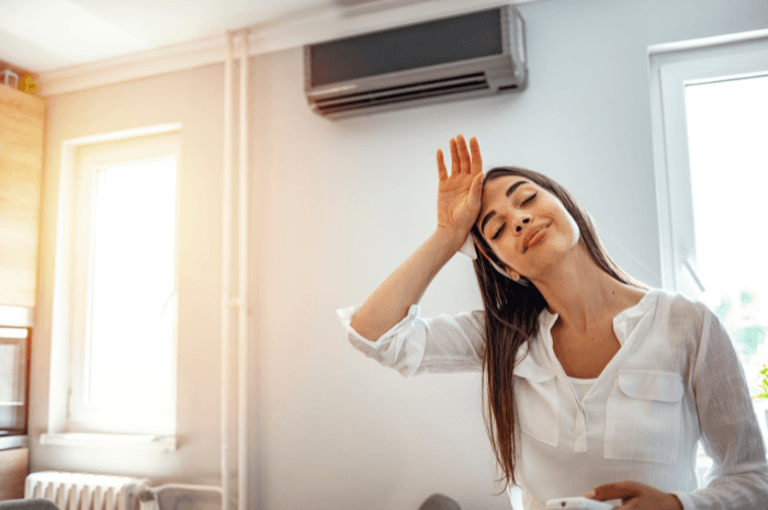 Femme qui a chaud devant un air climatisé mural