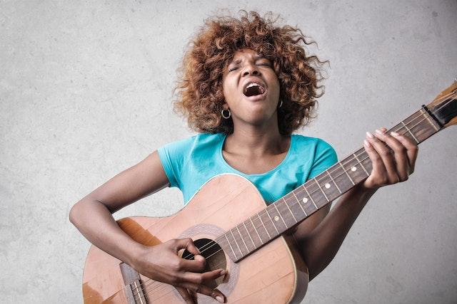 Femme noire jouant de la guitare et chantant à tue-tête pour déranger ses voisins