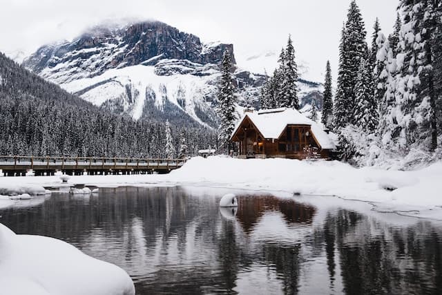 Maison sur le bord d'un ac, près d'une montagne enneigée
