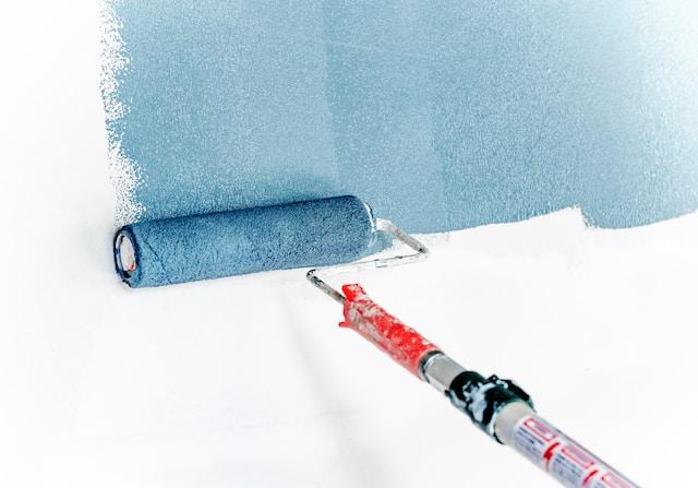 Rouleau étalant de la peinture bleue sur un mur