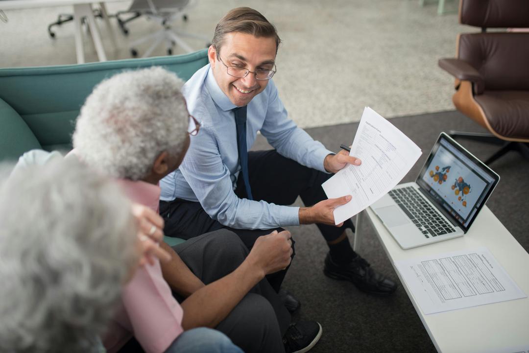 Agent d'assurance présentant un document à un couple de clients agés