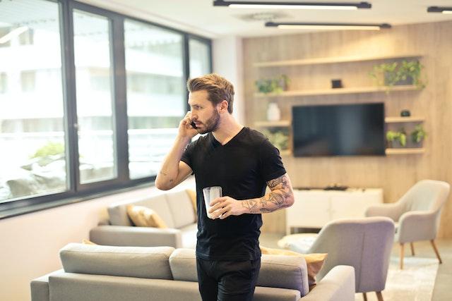 Homme dans son salon appelant son assureur au téléphone