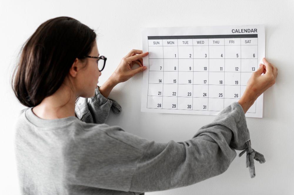 Femme affichant un calendrier au mur
