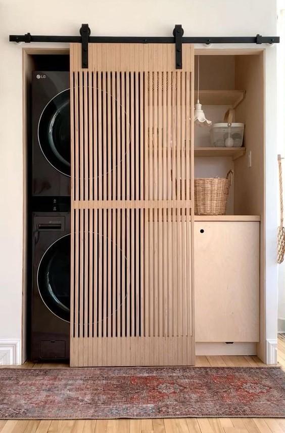 Laveuse et sécheuse cachées par une porte coulissante en bois