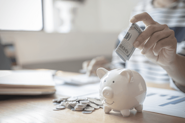 Personne économisant en mettant de l'argent dans une tirelire