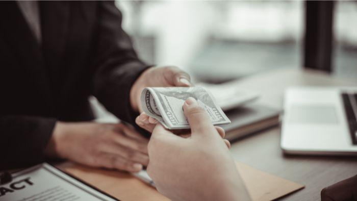 Client donnant une liasse d'argent à son prêteur hypothécaire