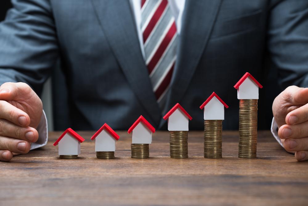 Petites maisons sur des piles d'argent devant un courtier hypothécaire