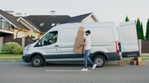 Homme déménageant seul ses boites devant un camion de déménagement blanc