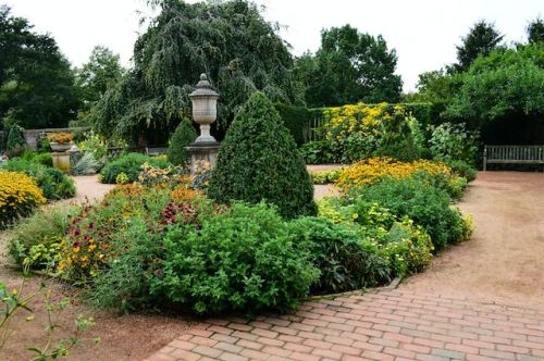 Jardin garni de fleurs et de buissons, avec une allée de briques