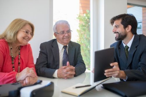Old couple with a mortgage broker looking at a document
