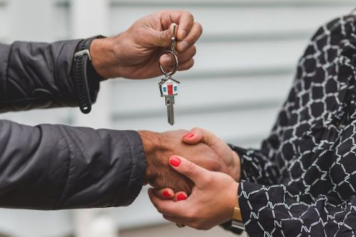 Courtier immobilier donnant la clé d’une maison à un acheteur