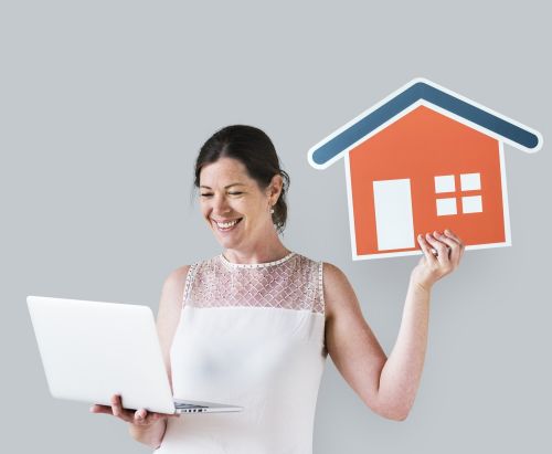 Femme tenant une image de maison et un ordinateur portable