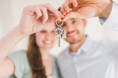 Jeune couple propriétaire-occupant tenant une clé