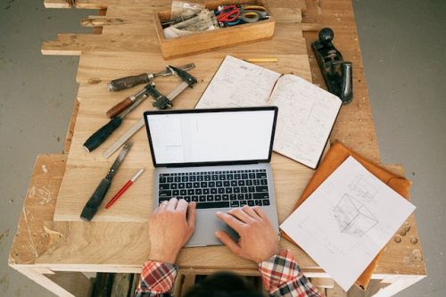 Entrepreneur en construction regardant un ordinateur sur une table remplie d’outils