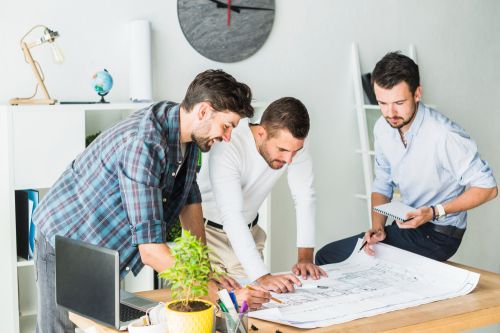 Trois technologues professionnels observant un plan sur un bureau