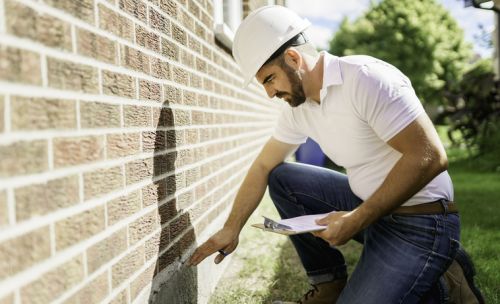 Inspecteur en bâtiment examinant les fondations d'un mur en brique